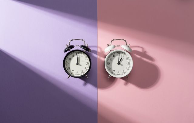 ピンクと紫の背景の前にある2つの時計